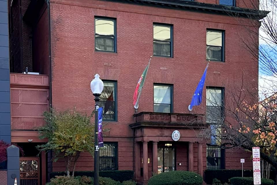 The Portuguese Embassy in Washington DC, a four-storey red brick building on Massachusetts Avenue, with the Portuguese and European Union flags flying above the entrance